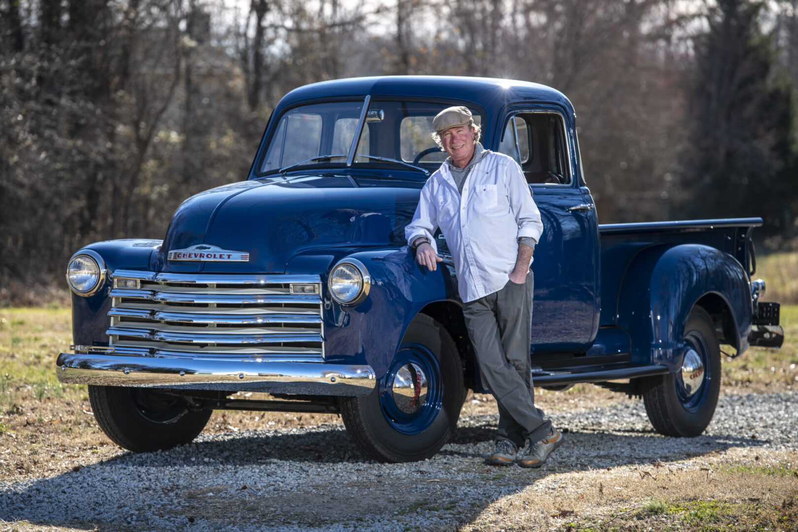 A man standing next to an old blue truck.