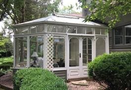 A white gazebo with a glass door and windows.