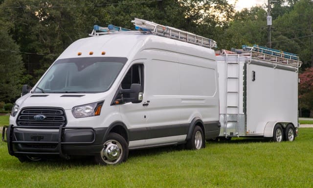 A white van is parked in the grass.