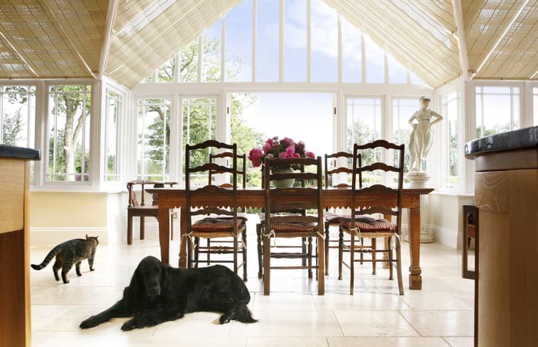 A black dog laying on the floor in front of a dining room table.