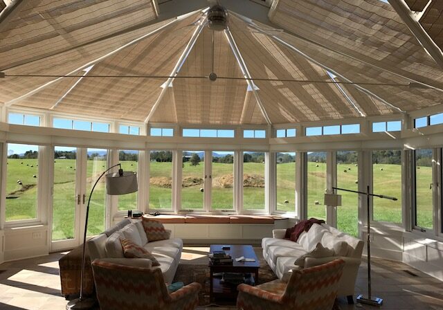 Bright sunroom with scenic views and custom woven roof shades.
